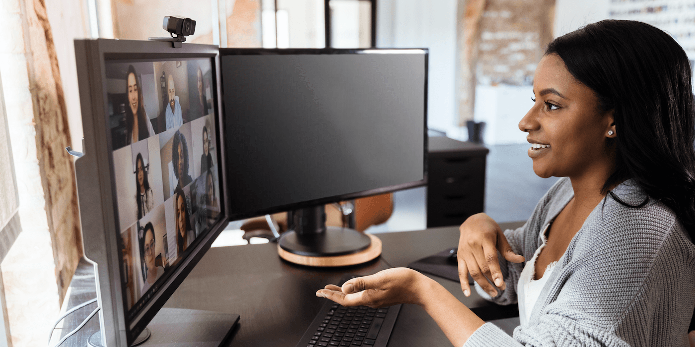 person sitting at a desk in front of a computer monitor on a video conference call