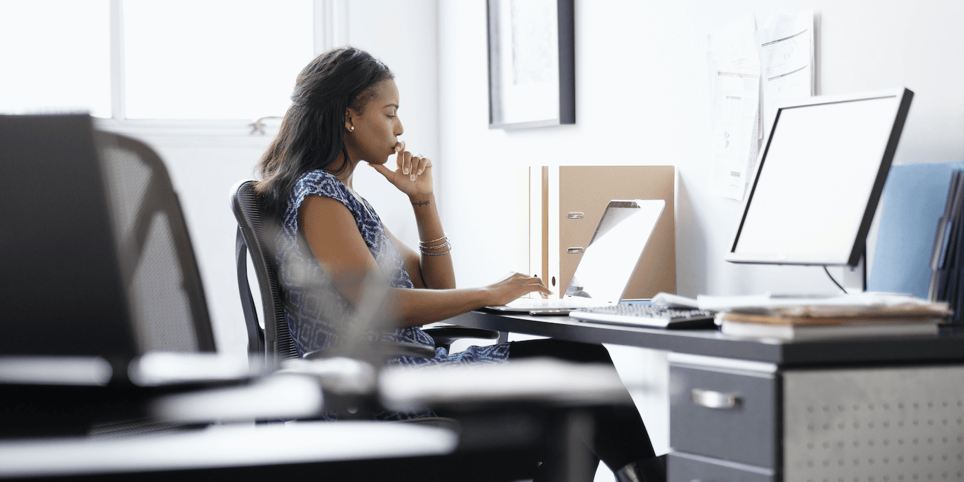 person sitting at their desk working on a laptop and thinking