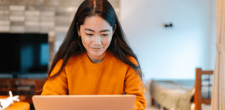young adult sitting at home working on a laptop