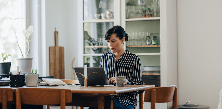 person sitting and working at home at a dining room table
