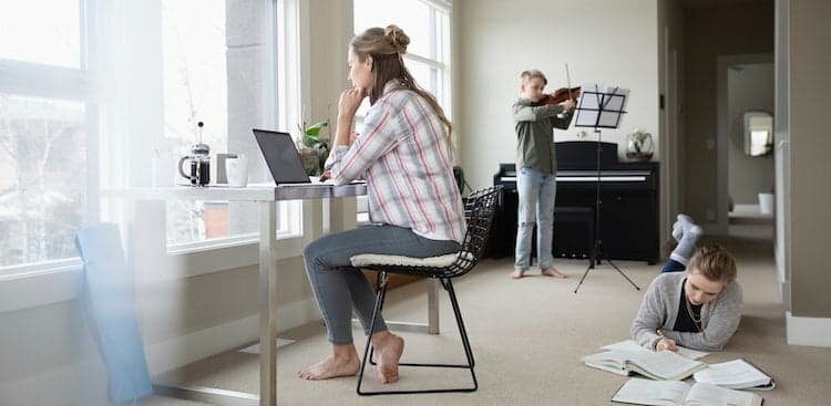 parent at computer with two kids in background courtesy Hero Images/Getty Images