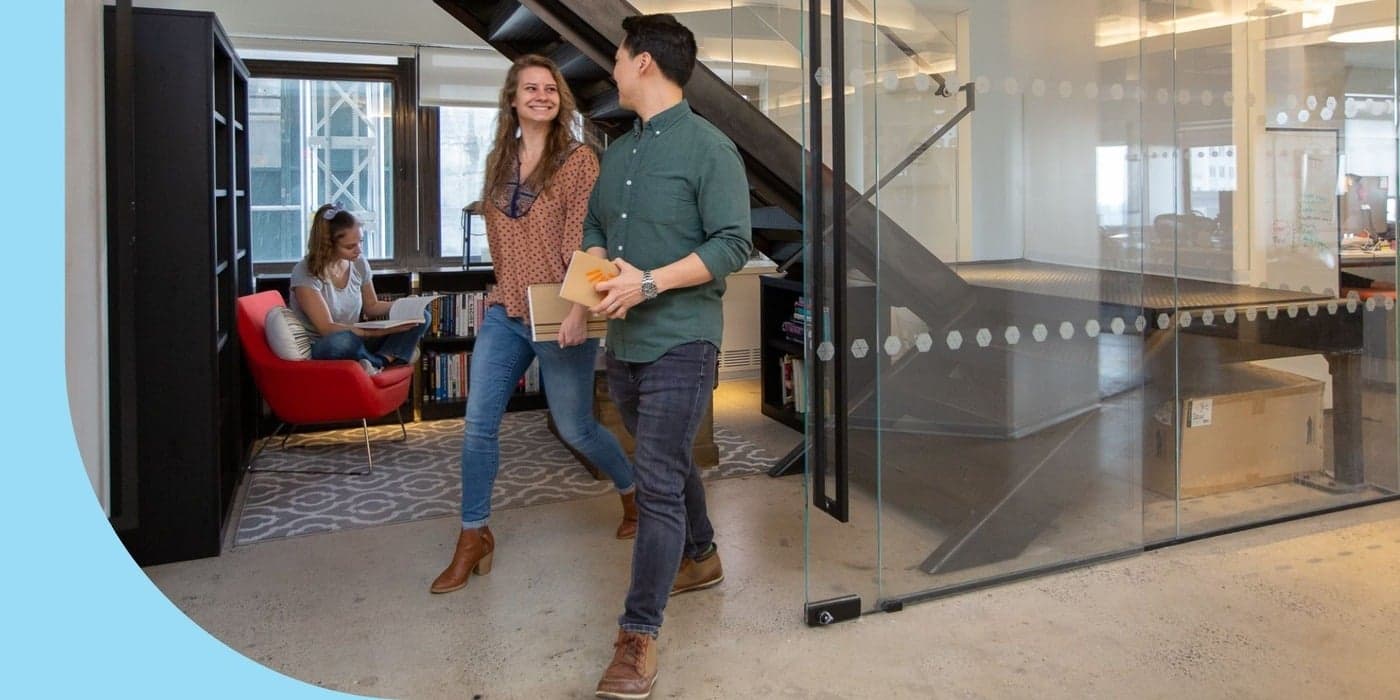 Two Coworkers walking inside an open-plan office space.